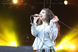 Charli XCX performing energetically on stage at the Positivus Festival 2013, with vibrant lighting highlighting her dynamic presence vS Taylor Swift Actually Romantic