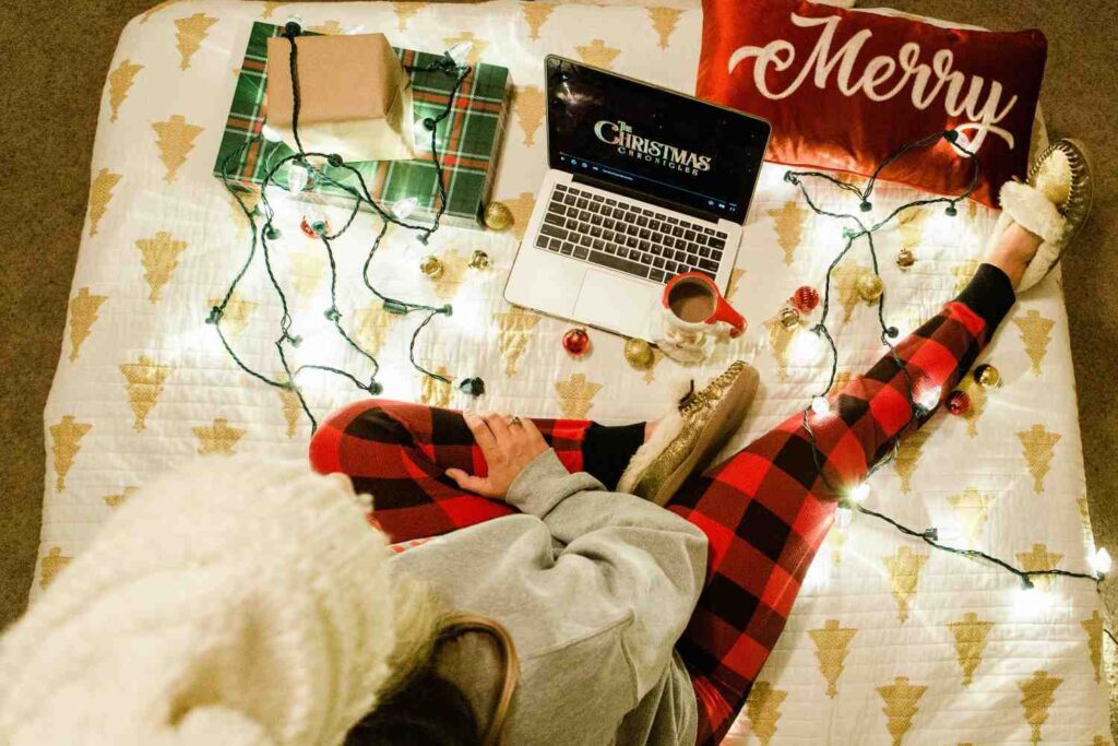Person relaxing on a bed while watching online streaming Disney plus content on a laptop