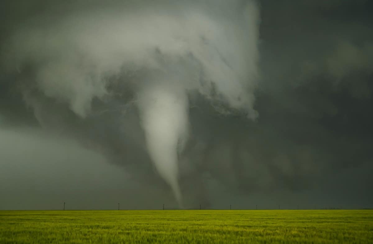 Massive dark storm clouds building over a green field before tornado formation